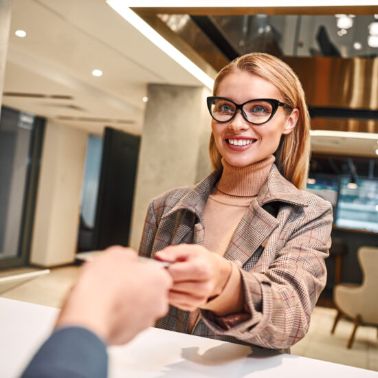 Check in hotel after long business trip. Close-up of woman in hotel check in at reception or front office being given key card.